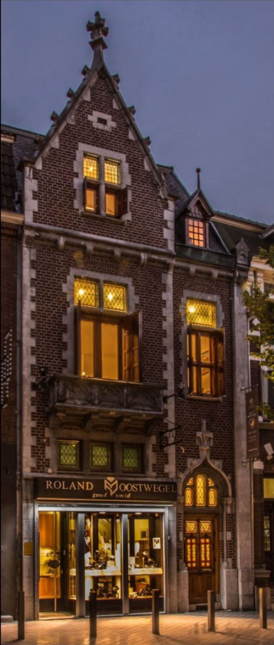 Exterieur van het historische atelier van R.O. Watches in Heerlen tijdens het blauwe uur, met warm verlichte etalage en klassieke gevel